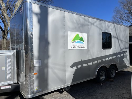 silver cargo trailer with green mountain mobile therapy logo on it