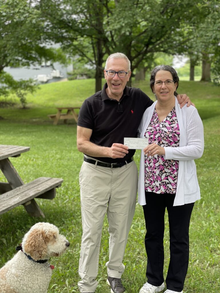 smiling man and woman holding a check